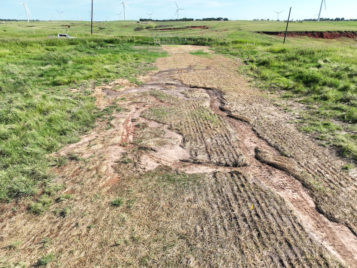 Rutted, eroded right-of-way with washed-out red soil and dead grass