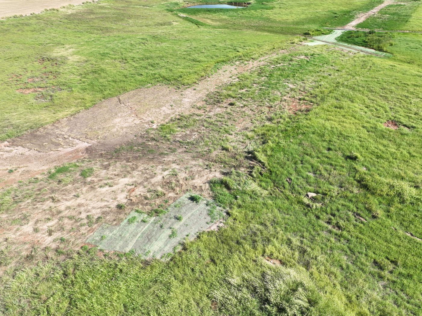 Patchy right-of-way with bare cracked soil and erosion matting